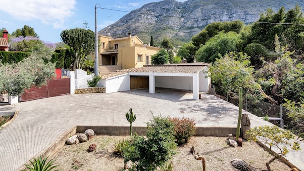 Un quartier résidentiel avec une maison, une allée pavée et une montagne en arrière-plan.