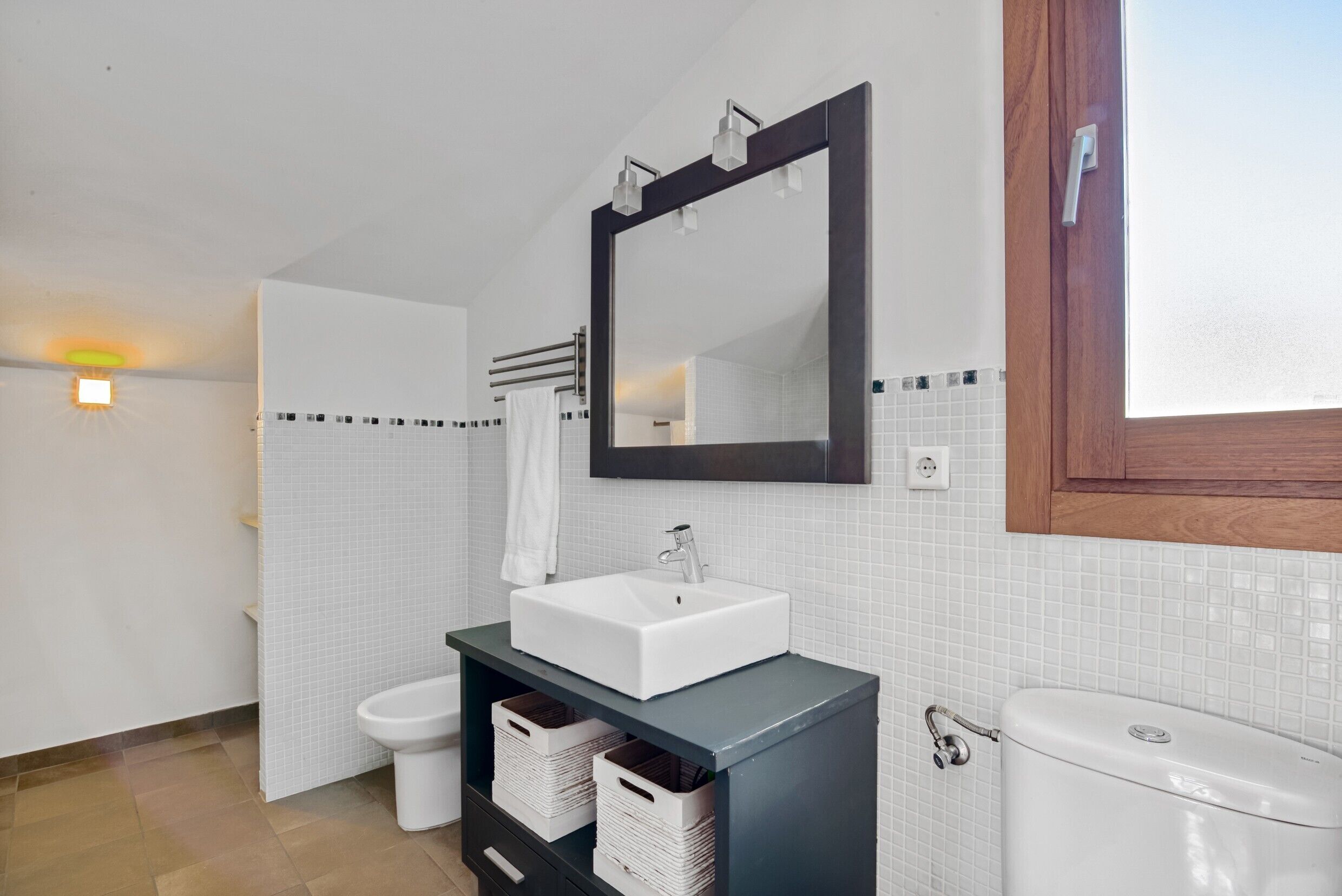 Une salle de bain moderne avec un lavabo blanc, un meuble-lavabo foncé et un grand miroir.