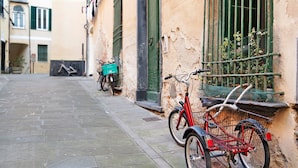 A narrow cobblestone street with a red bicycle leaning against a wall. - Holiday Apartment "Giomar" (levanto)