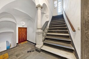 Eine imposante Treppe mit Holzwertlauf, weißen Säulen und einer Holztür am Oberende.