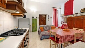 A compact kitchen with a stove, dining table, and a sofa in the background. - Holiday Apartment "Giomar" (levanto)