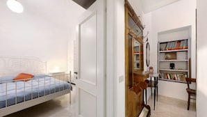 A bedroom with a bed, a wardrobe, a small table with chairs, and a bookshelf. - Holiday Apartment "Giomar" (levanto)