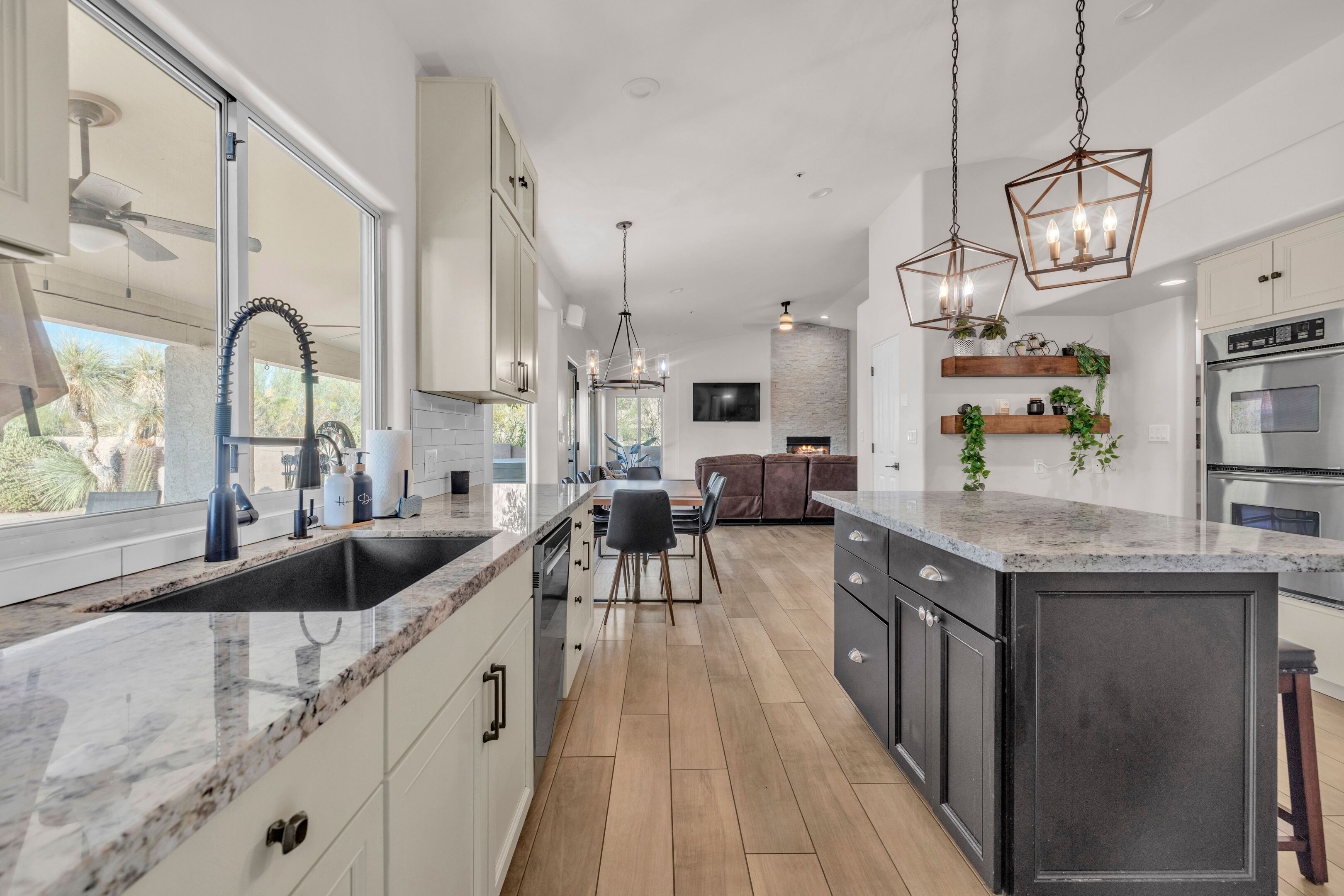 A modern kitchen with a large island, built-in appliances, and a dining area with a view.