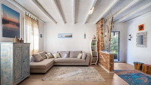 Una sala de estar con sofá modular, un mueble aparador, un tapete y una pared de ladrillo decorativa.