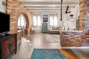 Un salon avec un téléviseur, un canapé et un mur en briques.