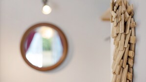 Ein runder Spiegel an der Wand, ein Holzbilde und eine Deckenleuchte.