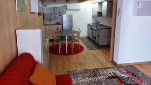 A compact living space with a dining area, kitchenette, and a sofa.