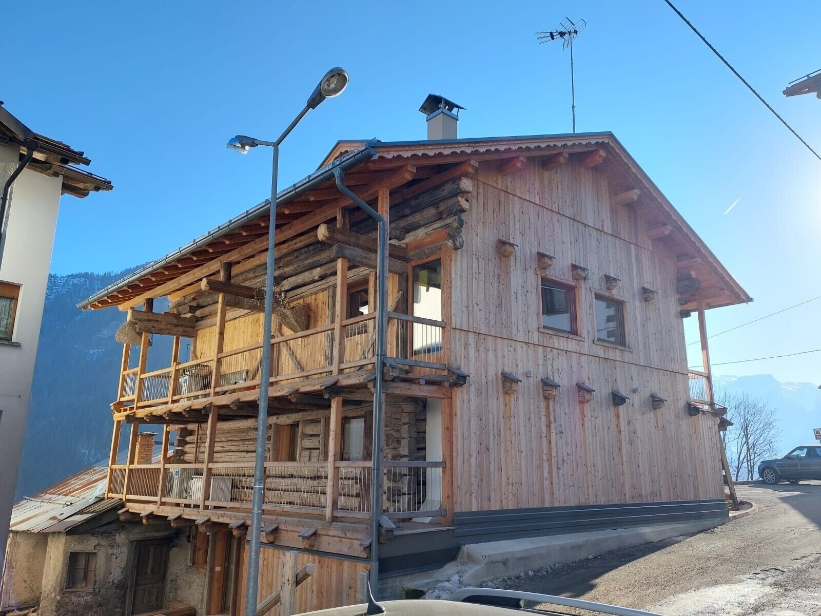 Eine Holzhütte mit Balkon, Schornstein und Bergblick.