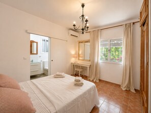 A bedroom with a bed, a desk, a chair, a mirror, and a window with curtains. - Villa 'Cerca De Puerto Banús' with Private Pool, Wi-Fi and Air Conditioning (Marbella)
