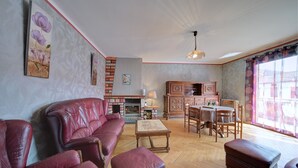 A living room with a fireplace, leather sofa, wooden dining table, and chairs.