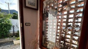 A room with a large window displaying a wooden lattice and various decorative items. A vase with dried plants is placed on the floor beside the window. - Lovely flat near the beach, terrace AV-04 (Roses)