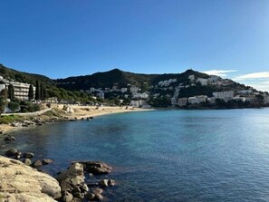 A coastal town with buildings on a hillside, a beach, and rocky shoreline. - Lovely flat near the beach, terrace AV-04 (Roses)