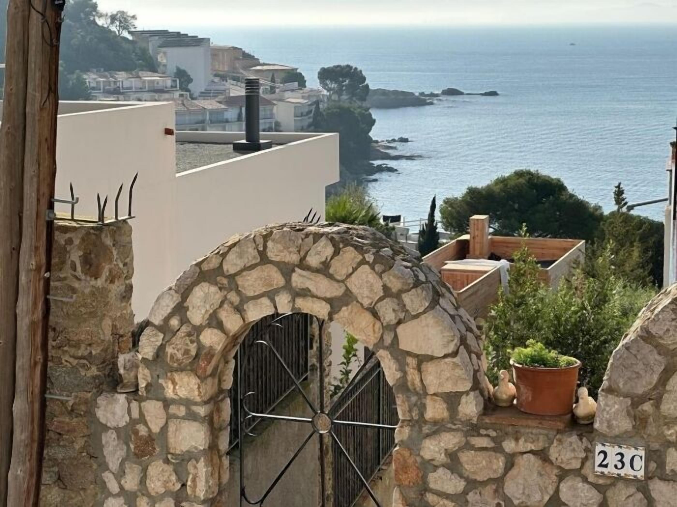 A stone archway with a metal gate, a potted plant, and a house number '23C'.