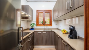 A modern kitchen with wooden cabinets, a built-in oven, a sink, and a coffee maker. - Villa Puerto Apartment with Mountain Views, Pool, and Wi-Fi (Sóller)