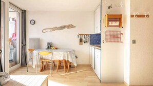 A compact kitchen with a dining table, chairs, and a small refrigerator. - Lovely vacation home Séjour grand ski (Huez)