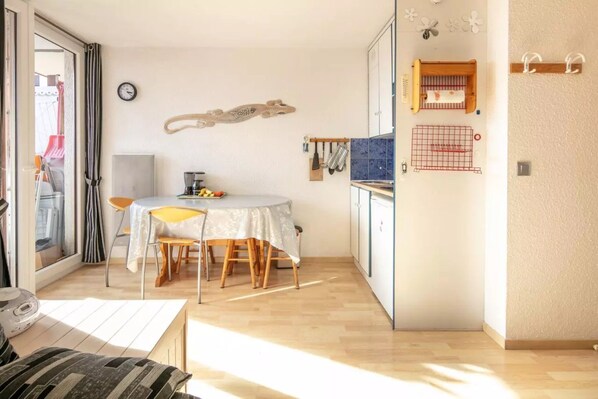 A compact kitchen with a dining table, chairs, and a small refrigerator.