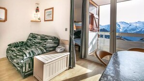 A cozy room with a sofa, a table, and a view of mountains. - Lovely vacation home Séjour grand ski (Huez)