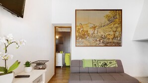 Un salon moderne avec un canapé, un tableau, un téléviseur et une plante en pot.