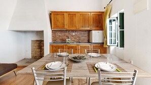 Un coin repas avec une table en bois dressée pour quatre personnes, un mur en briques et des placards en bois au-dessus.