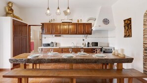 Une cuisine avec des meubles en bois, un plan de travail en granit et une table à manger pour quatre personnes.