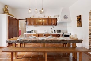 A kitchen with wooden cabinets, a granite countertop, and a dining table set for four. - Casa Castelão – Retreat Among Vineyards with Lounge, Football Field & Shared Pool (Palmela)