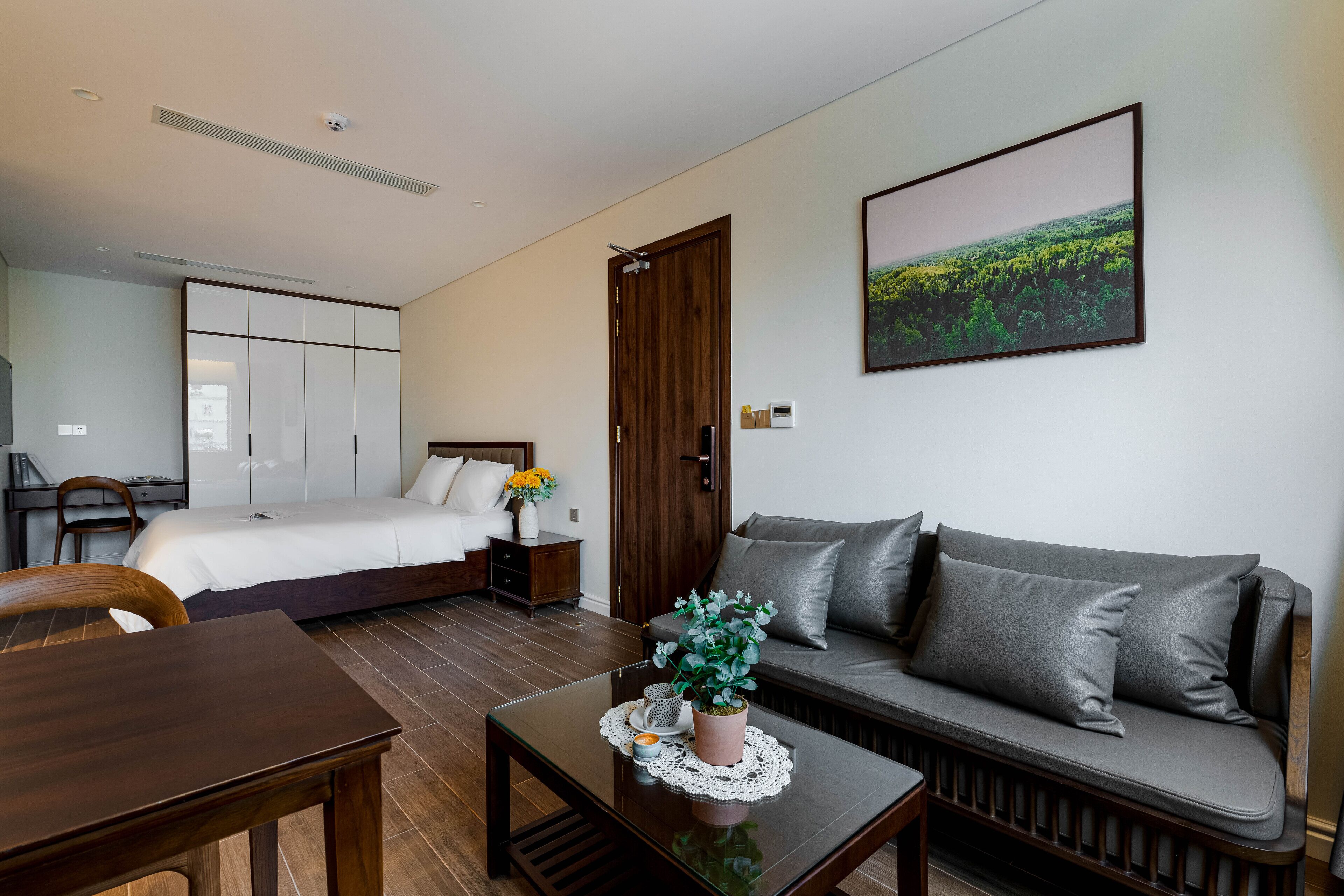 Une chambre d’hôtel moderne, équipée d’un lit, d’un canapé, d’une table à manger et d’une plante en pot.