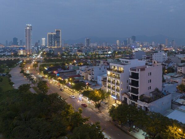 A cityscape with modern buildings, a wide road, and streetlights.