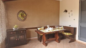 Un comedor con mesa de madera y banco, un adorno en la pared y un mueble con cajones.