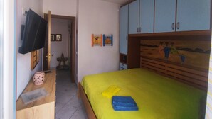 Un dormitorio con cama, ventilador de techo, televisor y armario.