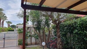 Un espacio al aire libre cubierto con suelo de baldosas, una verja metálica y una fila de bicicletas rojas estacionadas junto a una pared.