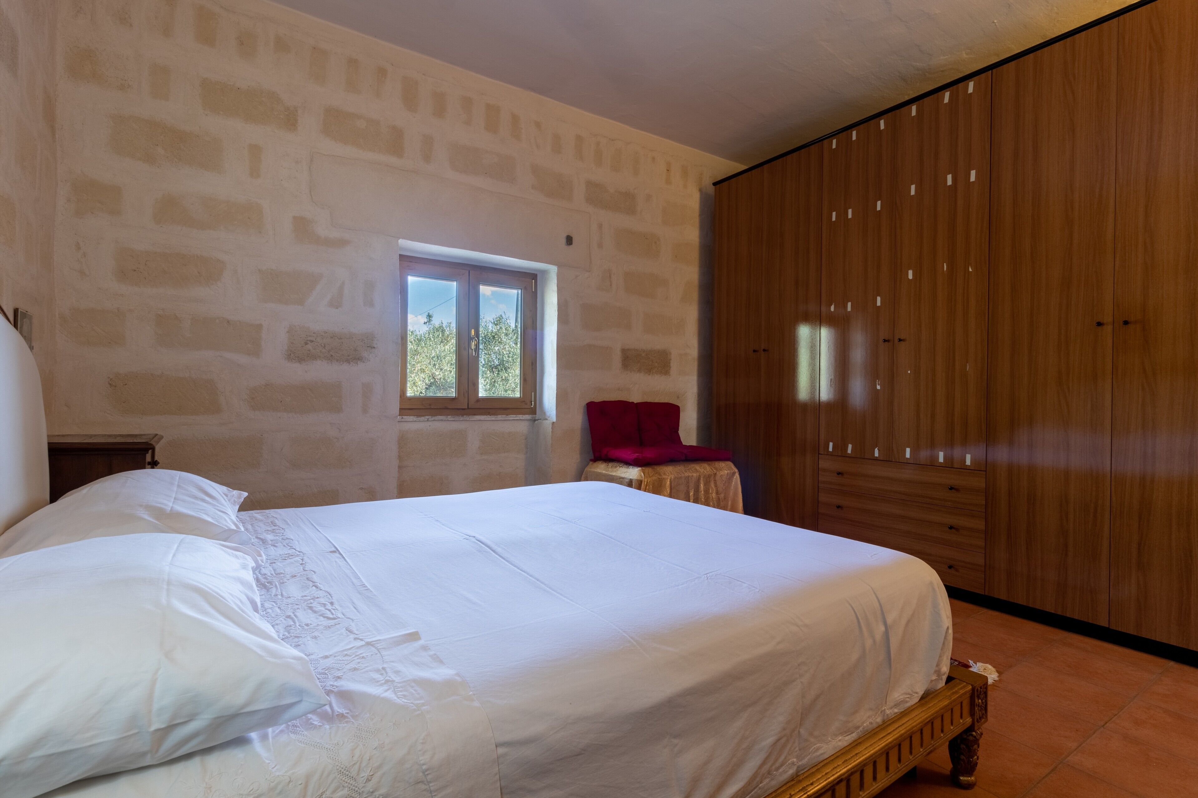 Een slaapkamer met een bed, een houten kledingkast en een raam.