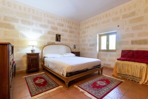 A bedroom with a bed, nightstand, lamp, and a window.