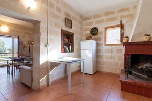 A compact kitchen with a dining area, a fireplace, and a window.