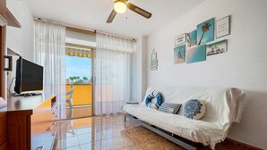 Un soggiorno moderno con divano, televisore e ventilatore a soffitto.