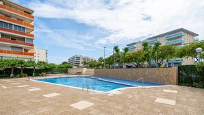 Una piscina con bordo in pietra, circondata da edifici e vegetazione.