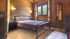 Une pièce en bois avec un lit, une fenêtre, un miroir et un luminaire fixé au mur.
