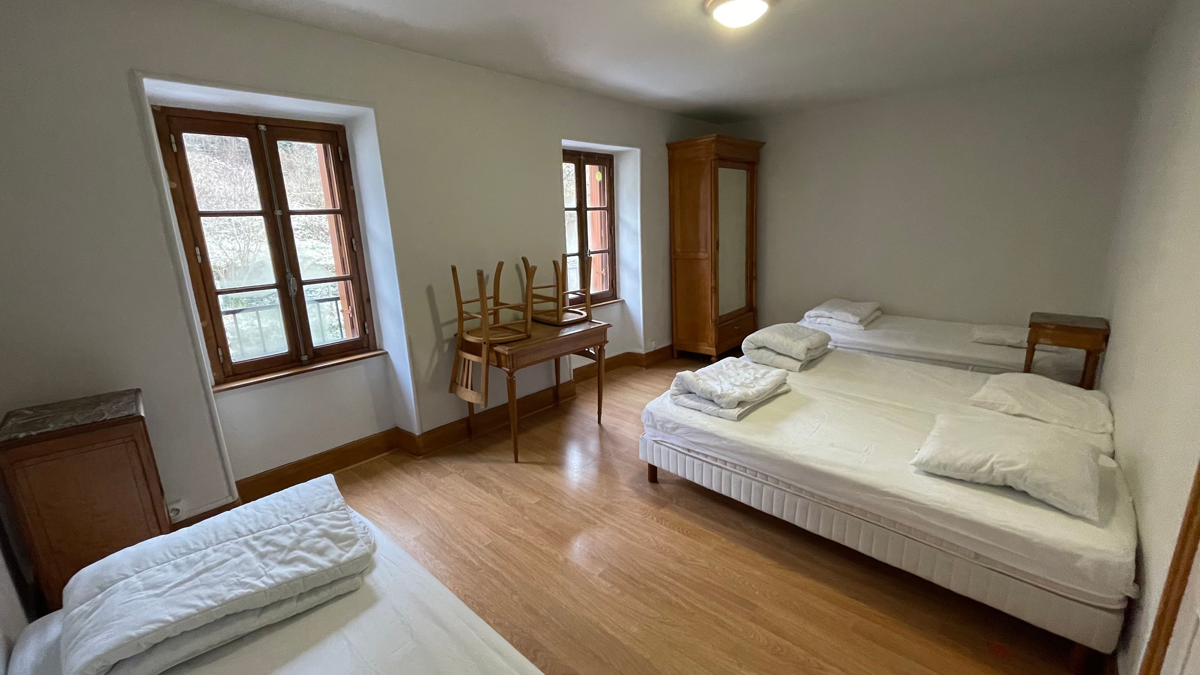 A bedroom with a double bed, a desk, two chairs, and a wardrobe.