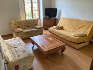 A living room with two sofas, a coffee table, and a television on a wooden cabinet.