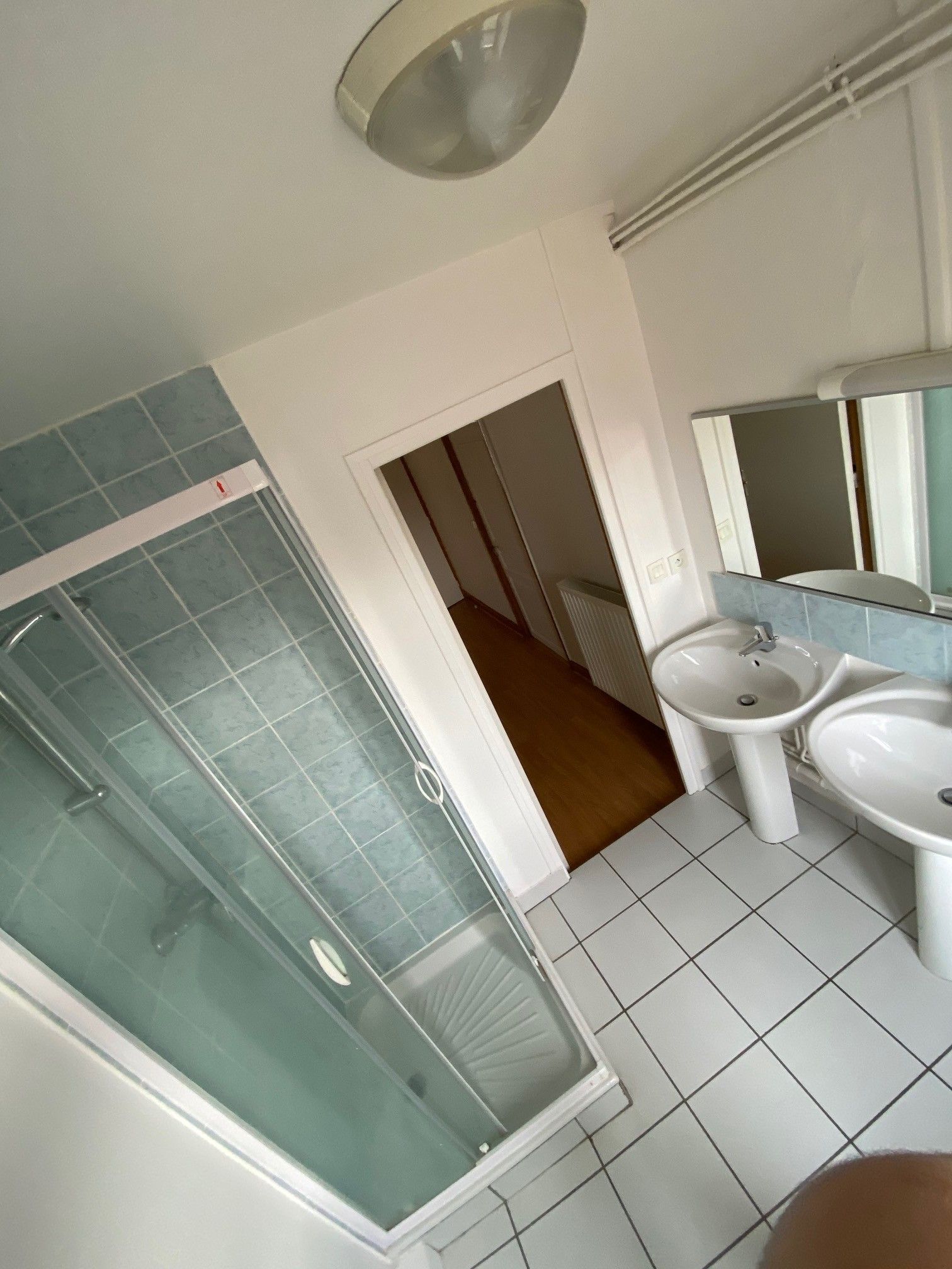 Ein Badezimmer mit einer Duschkabine, einem Waschbecken und einem Spiegel.
