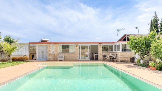 A swimming pool with a house in the background, a covered patio, and a clear sky. - Apartment 'Dependance Con Piscina' with Private Pool, Wi-Fi and Air Conditioning (taurisano)