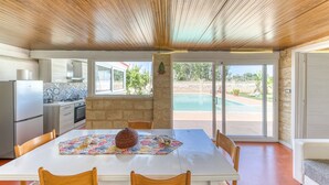 A spacious dining area with a white table, wooden chairs, and a decorative centerpiece. - Apartment 'Dependance Con Piscina' with Private Pool, Wi-Fi and Air Conditioning (taurisano)