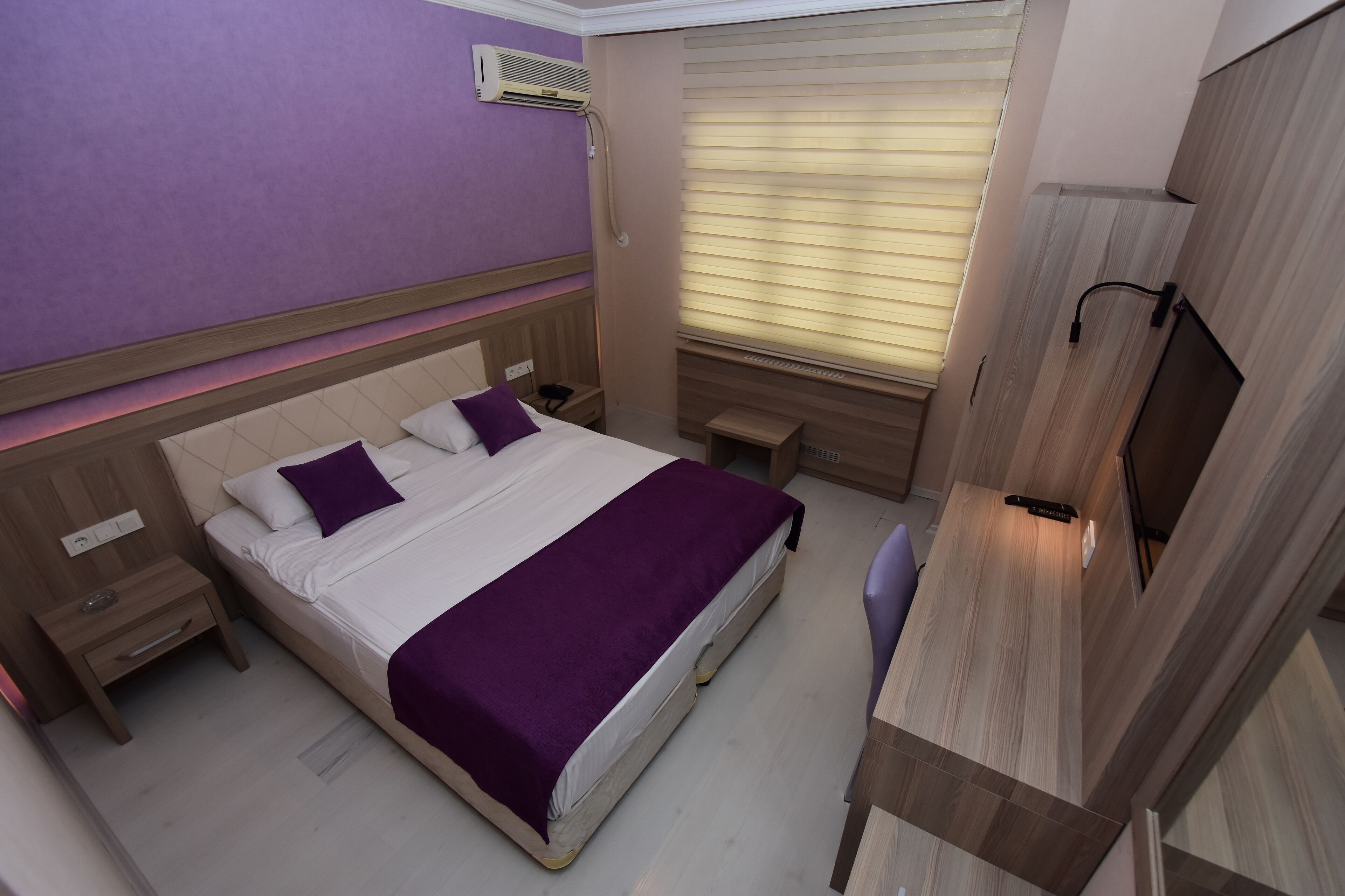 Une chambre d’hôtel avec un lit, des tables de chevet, un bureau et une télévision.