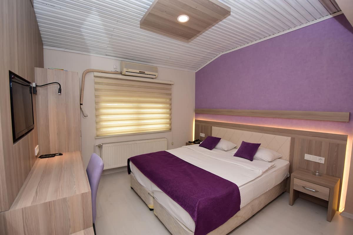 Un dormitorio moderno con cama, mesitas de noche, escritorio y televisor.