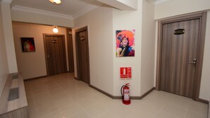 Un pasillo de hotel con puertas de madera, un extintor y un cartel en la pared.
