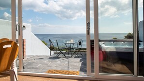 Un balcón con mesa y sillas, un jacuzzi y vista al mar.