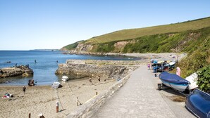 Une plage côtière avec des bateaux, un mur de pierre et un ciel dégagé.