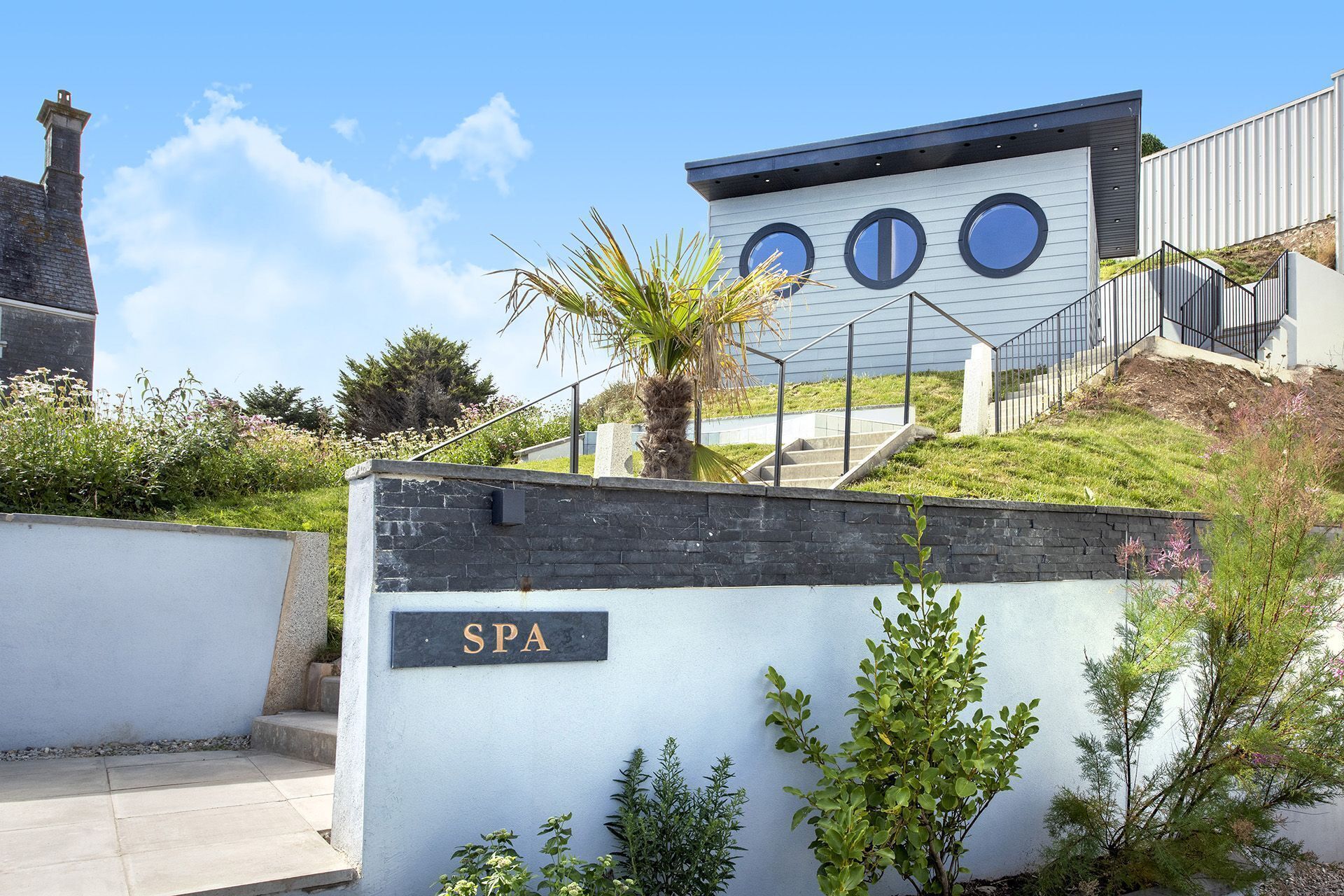 A spa building with a sign, a staircase, and a palm tree.