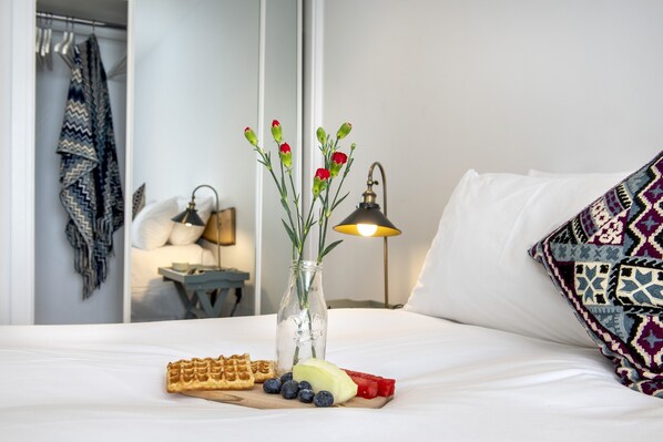 A neatly made bed with a tray of waffles, blueberries, and watermelon slices. A vase with flowers and a lamp are also visible. - Fulmar - Beachside House with Terrace Hot Tub & Fantastic Views (Portwrinkle)