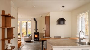 Una cocina moderna con una isla central, estanterías de madera y un estufa de leña empotrada.