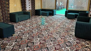 A room with patterned carpet, green sofas, and a chandelier. - The Heritage Safina Group Of Houseboats (Srinagar)